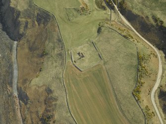 Oblique aerial view centred on the remains of the church and the churchyard, taken from the W.