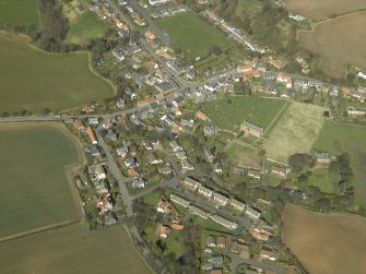 General oblique aerial view of the village, centred on the remains of the priory and the church, churchyard and manse, taken from the SE.