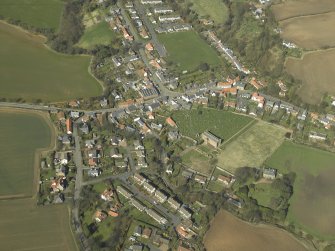 General oblique aerial view of the village, centred on the remains of the priory and the church, churchyard and manse, taken from the SE.