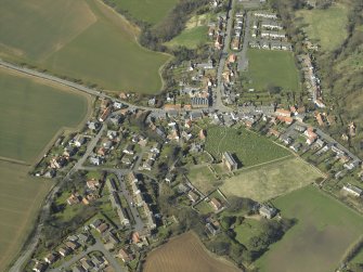 General oblique aerial view of the village, centred on the remains of the priory and the church, churchyard and manse, taken from the ESE.