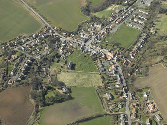 General oblique aerial view of the village, centred on the remains of the priory and the church, churchyard and manse, taken from the ENE.