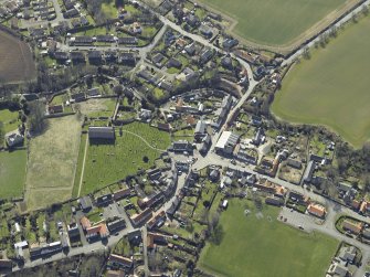 General oblique aerial view of the village, centred on the remains of the priory and the church, churchyard and manse, taken from the NNW.