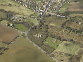 General oblique aerial view centred on the church, burial-ground, war memorial, gatelodge and remains of the church, taken from the ESE.