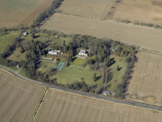 Oblique aerial view centred on the country house, walled garden, gate-lodges and cottage, taken from the SE.