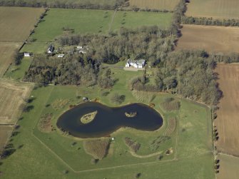 Oblique aerial view centred on the country house with the walled garden, cottages, barn and stable adjacent, taken from the SE.