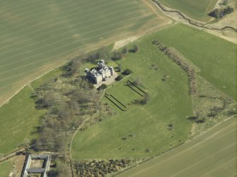 Oblique aerial view centred on the country house, stable block and landscaped gardens, taken from the W.