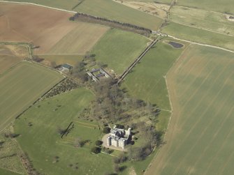 Oblique aerial view centred on the country house, stable block and landscaped gardens with the gate and gate lodge adjacent, taken from the SE.