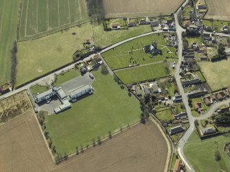 Oblique aerial view centred on the school with the church, burial ground and dovecot adjacent, taken from the N.