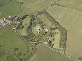 Oblique aerial view centred on the country house and walled garden with the gate-lodge and road bridge adjacent, taken from the SE.