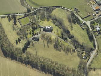 Oblique aerial view centred on the country house and walled garden with the gate-lodge and road bridge adjacent, taken from the NNE.