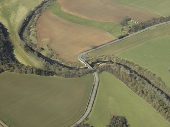 Oblique aerial view centred on the road bridge with the remains of the church and burial-ground adjacent, taken from the SE.