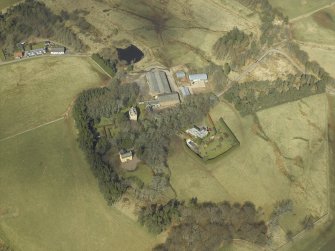 Oblique aerial view centred on the remains of the tower-house and the farmsteading, stable and farmhouse, taken from the SSW.