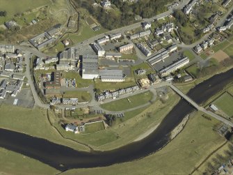 Oblique aerial view centred on the woollen mill with the road bridge adjacent, taken from the SW.
