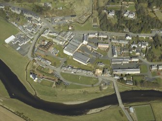 Oblique aerial view centred on the woollen mill with the road bridge and convent  adjacent, taken from the S.