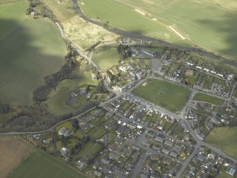 Oblique aerial view of the village centred on the hall with the church and monument adjacent, taken from the SE.