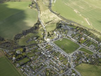 Oblique aerial view of the village centred on the hall with the church and monument adjacent, taken from the ESE.
