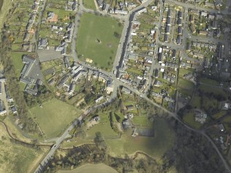 Oblique aerial view of the village centred on the hall with the church and monument adjacent, taken from the WSW.