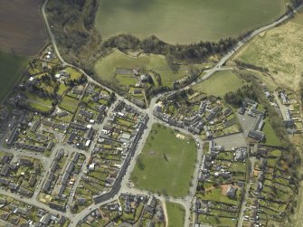 Oblique aerial view of the village centred on the hall with the church and monument adjacent, taken from the NE.