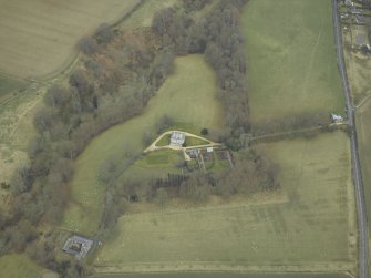 Oblique aerial view centred on the country house with stables, gate-lodge, gate piers and gates adjacent, taken from the SW.