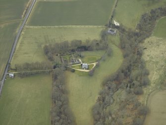 Oblique aerial view centred on the country house with stables, gate-lodge, gate piers and gates adjacent, taken from the NE.