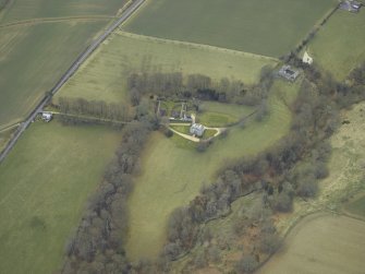 Oblique aerial view centred on the country house with stables, gate-lodge, gate piers and gates adjacent, taken from the NNE.
