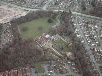 Oblique aerial view centred on the house and walled garden with the gate lodge adjacent, taken from the SW.