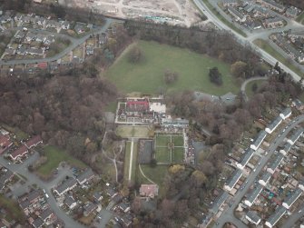 Oblique aerial view centred on the house and walled garden with the gate lodge adjacent, taken from the S.