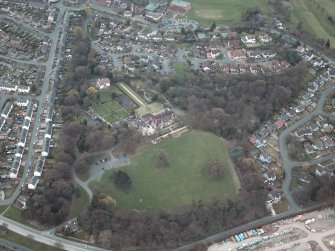 Oblique aerial view centred on the house and walled garden with the gate lodge adjacent, taken from the N.