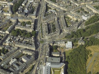 Oblique aerial view centred on the bank and tenements with the school and church adjacent, taken from the SW.