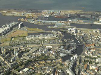 General oblique aerial view centred on the offices, road bridges, swing bridge, harbour, dock and shed, taken from the SW.