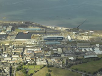Oblique aerial view centred on the dock, dry dock and the railway station with Leith Links in the foreground, taken from the WSW.