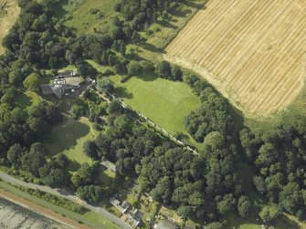 Oblique aerial view centred on the country house, cottage and church, taken from the SE.