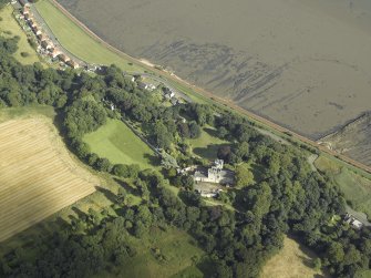 Oblique aerial view centred on the country house, cottage and church, taken from the WNW.