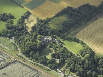 Oblique aerial view centred on the country house, cottage and church, taken from the ESE.