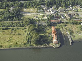 Oblique aerial view of the remains of the shipyard centred on the buildings and pier, taken from the S.