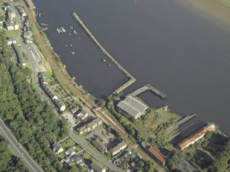 Oblique aerial view of the remains of the shipyard centred on the buildings and piers, taken from the NW.