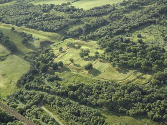 Oblique aerial view centred on the remains of Rough Castle Roman fort and the course of the Antonine Wall, taken from the SE.