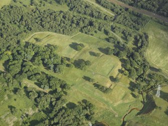 Oblique aerial view centred on the remains of the Roman fort and the course of the Antonine Wall, taken from the NW.