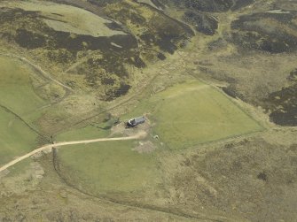 Oblique aerial view centred on the farmstead with the remains of the building adjacent, taken from the NW.