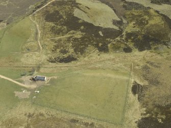 Oblique aerial view centred on the farmstead with the remains of the building adjacent, taken from the W.