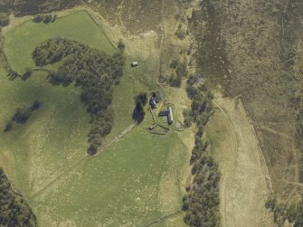 Oblique aerial view centred on the farmhouse and farmsteading with the remains of the farmstead adjacent, taken from the N.