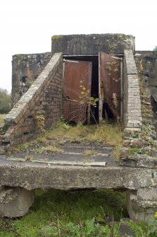 Detail.  Entrance to exposed concrete and brick magazine showing metal doors and tramway sleepers still in situ from SW.