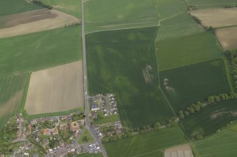 Oblique aerial view centred on the cropmarks of the possible henge, possible barrow and rig with the brewery adjacent, taken from the WSW.