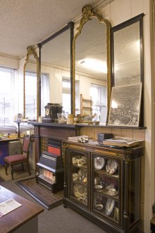 Interior. Ground floor. Back shop, detail office area. Fireplace and wall mirrors and late 19th century display cabinet.