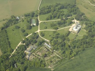 Oblique aerial view centred on the country house with the walled gardens and stables adjacent, taken from the ESE.