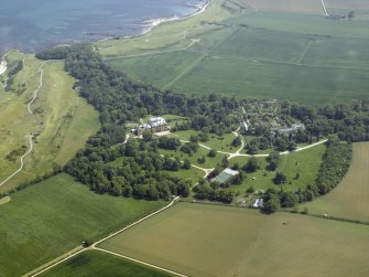 General oblique aerial view centred on the country house, walled gardens and stables, taken from the W.