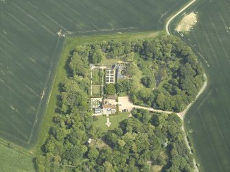 Oblique aerial view centred on the country house, stable block, dovecot and walled garden, taken from the W.