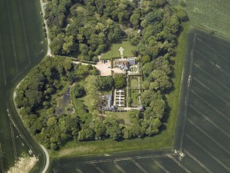 Oblique aerial view centred on the country house, stable block, dovecot and walled garden, taken from the E.