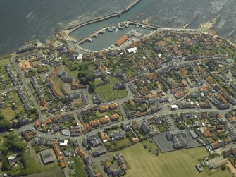 Oblique aerial view of the village centred on the priory, church, tollbooth and burial ground with the harbour adjacent, taken from the NNW.