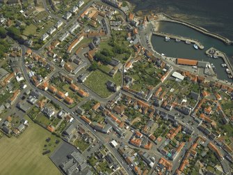 Oblique aerial view of the village centred on the priory, church, tollbooth and burial ground with the harbour adjacent, taken from the NW.